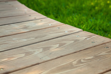 Fototapeta premium Wooden table in diagonal on the image with blurred summer green background