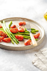 asparagus, tomatoes salad on ceramic plate with fork