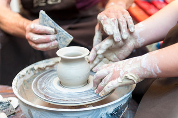 Handcrafted, Hands make clay. Master teaches the student to make pitcher on pottery wheel.