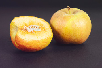 rotten apple on black in top view. Apple biting rotten bruise.