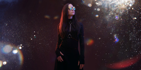 Portrait of mysterious sensual beautiful brunette woman in futuristic black dress on dark space...