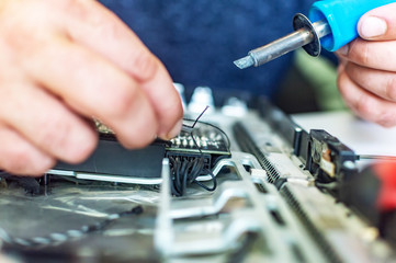 a man repairs a computer, solders a board, repairs electronics and modern technologies