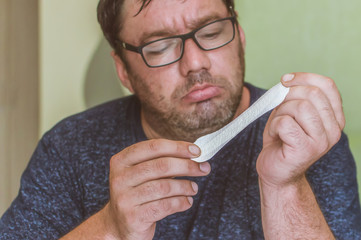 a man with glasses looks at a feminine sanitary pad with surprise