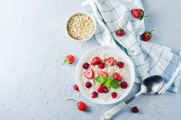 Obraz na płótnie Canvas Oatmeal porridge with fresh strawberries and raspberries