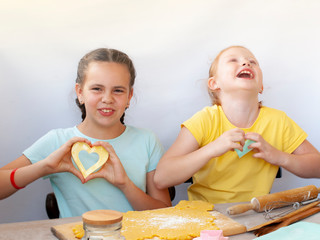 Two children a girl make cookies from dough. Two funny cheerful girls. Natural homemade food.