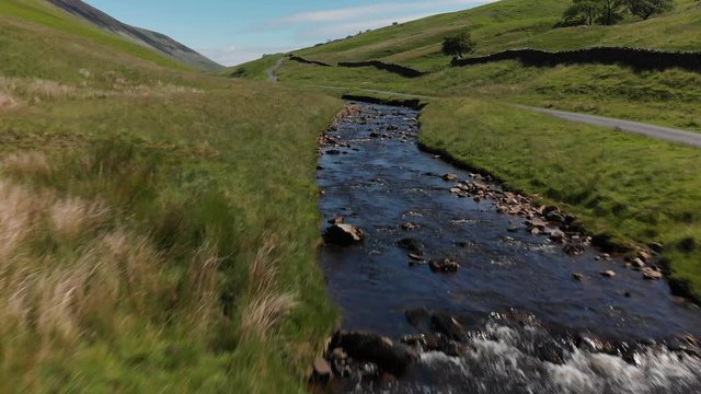 A low altitude, moderate speed flyover of Barbon Beck, Carnforth, Lancashire, England. This stunning countryside features a stream running alongside a small country lane.