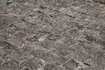 Abstract background of gray cobblestone pavement in light in perspective.