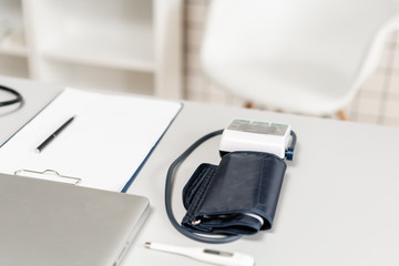 Workplace of doctor with laptop, stethoscope and notebook on wooden table in the office. Blood Pressure Monitor. Medical equipment. Cardiac diagnosis. vintage tone.