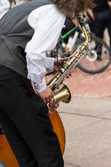 Street musician's hands playing saxophone in an urban environment.