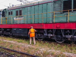 Obraz premium The Machinist of a diesel locomotive conducts locomotive maintenance on a sunny summer day.
