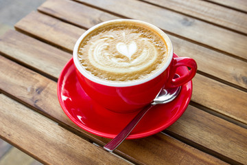 Red cup of cappuccino with croissant on a table in an outdoor cafe. Tipical italian breakfast. Selective focus