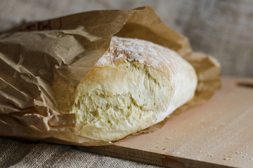 Fresh bread on an oak board wrapped in paper
