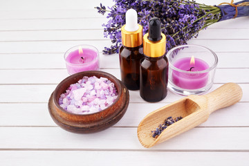 essential oil and lavender flowers on wooden table