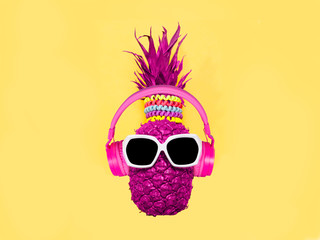Pineapple in pink headphones and glasses on a yellow background