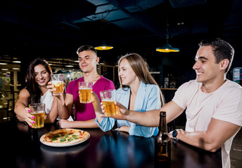 Cheerful friends in the pub. Drinking beer, wine and whisky, talking, having fun.