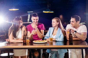 Cheerful friends in the pub. Drinking beer, wine and whisky, talking, having fun.