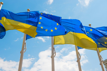 Row of flag poles with European Union and Ukraine flags fluttering by wind on blue sky background - obrazy, fototapety, plakaty