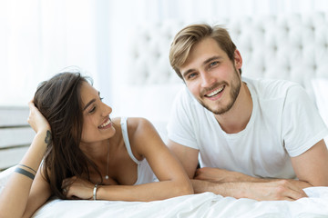 Young happy couple lying together in bed.