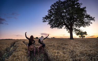 Portrait of a beautiful young women in black bodysuit on meadow watching the sunset enjoying nature