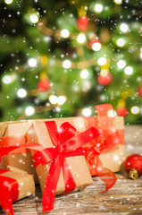 Christmas gift boxes against the background of Christmas tree and bokeh of twinkling party lights.