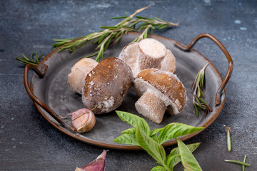 Frozen penny bun mushrooms in metal tray on grunge table, closeup