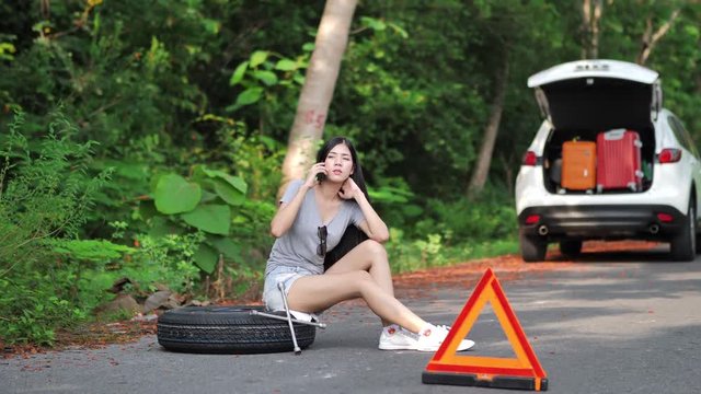 Young asian women tourist near a broken car on the country road is calling on smart phone Asking for Help.