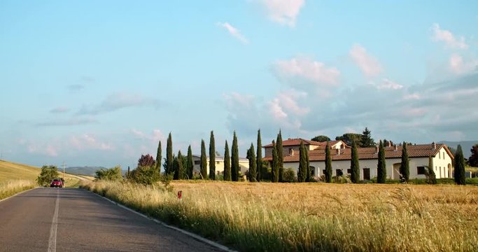 Traveling around beautiful Val d&rsquo;Orcia valley in the countryside in summer. View from car driving on the road against amazing architecture and landscape of italian region. Roadtrip to Tuscany, Italy.