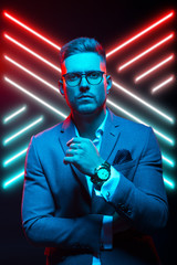 Young handsome model posing in a studio in a trendy neon light. Fashionable man in a stylish suit. Vibrant color. Bright colorful light effects. Disco style. Overlay. Gel filter. Supersaturated