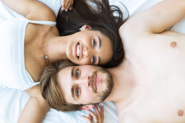 Close-up of happy couple is lying in bed together. Enjoying the company of each other.