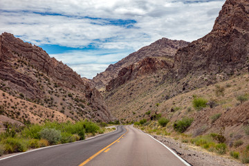 Long winding highway with ups and downs, cloudy blue sky. Valley of Fire Nevada, USA