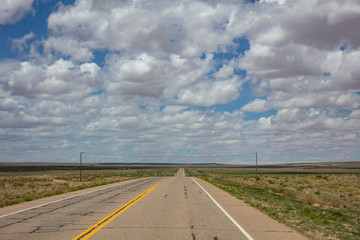 Long highway in the american desert, cloudy blue sky
