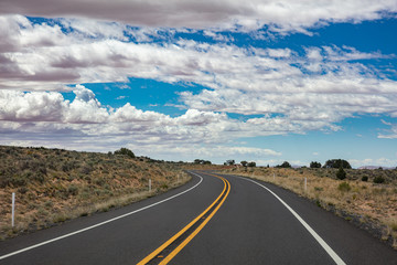 Fototapeta na wymiar Long winding highway in the american countryside, blue sky with clouds