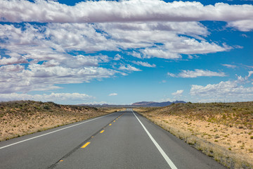 Long highway with ups and downs, cloudy blue sky. USA