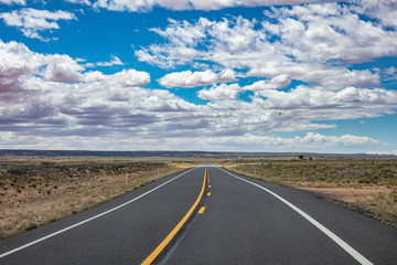 Long highway with ups and downs, cloudy blue sky. USA