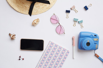 Vacation background with straw hat, pink sunglasses, instant camers, clippers, smartphones and notepad