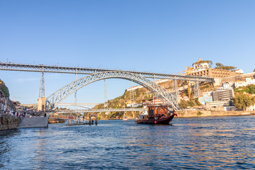 Naklejka premium Tourist boat in Porto, Portugal, in front of Dom Luis Bridge