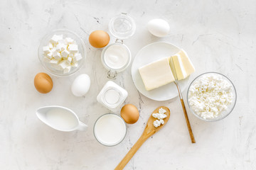Dairy products from farm with milk, eggs, cottage, butter, yougurt on white marble background top view