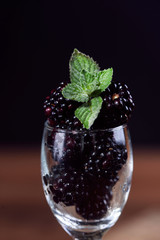 Ripe and tasty blackberries in a glass goblet with mint leaf
