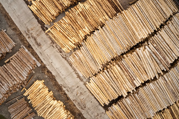 Aerial view of sawmill and chopped tree wood log stacks in a row with machinery