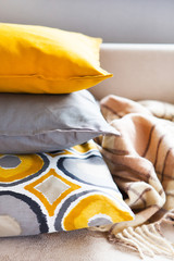 Cushions and plaid on the beige sofa close up with copy space. Sweet home and cozy concept