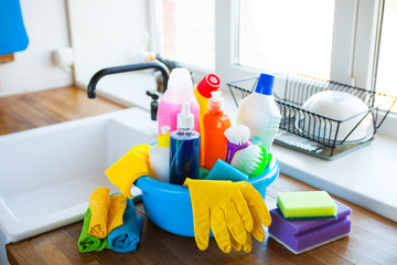 Basket with cleaning items on blurry background white citchen. Cleaning concept. - 279709548