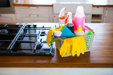 Basket with cleaning items on blurry background white citchen. Cleaning concept.