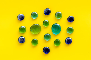 Shiny glass stones for decoration, creativity and craft on yellow background top view