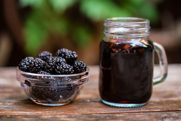 Close up fresh mulberries fruit in bowl and juice in jar