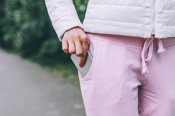Woman's hand put smartphone in not zippered pocket on pants. Danger of dropping.