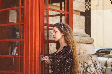 Young woman with closed eyes near telephone cabin