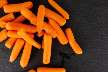 Lot of whole peeled orange baby cut carrot flatlay on grey stone