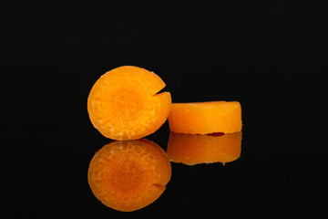 Group of two slices of peeled orange baby cut carrot isolated on black glass