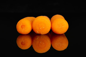 Group of three whole peeled orange baby cut carrot in line isolated on black glass