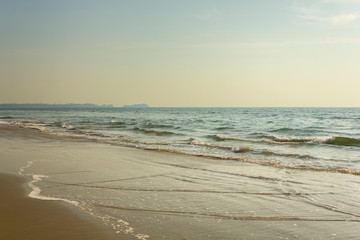 Fototapeta na wymiar yellow sandy beach against the backdrop of the foam of the ocean waves under a clear sky